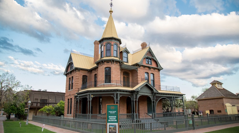 A picture of Rosson House Museum - a Queen Anne style brick home with green trim and a yellow roof, built in Phoenix, AZ in 1895.