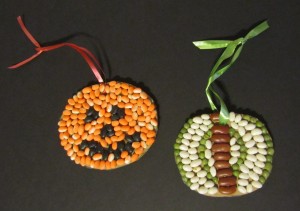 Two finished ornaments: one resembling a Halloween Jack-o-lantern, and the other simple lines and curves in different colors.