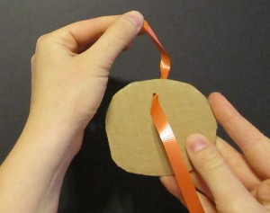 Threading ribbon through the hole in the cardboard form.