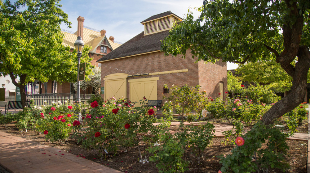 The Visitor Center at Heritage Square, with the Memorial Rose Garden in the foreground and Rosson House in the background.