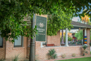 A picture of The Bungalow museum store, with a green and gold Heritage Square banner in the foreground.