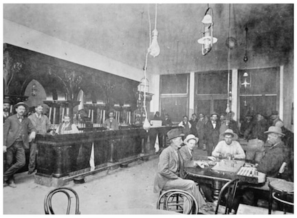 An old, black and white photo of a late 19th century saloon in Jerome, Arizona. It shows the interior with several men sitting at tables, standing at and behind the bar, and in the background.