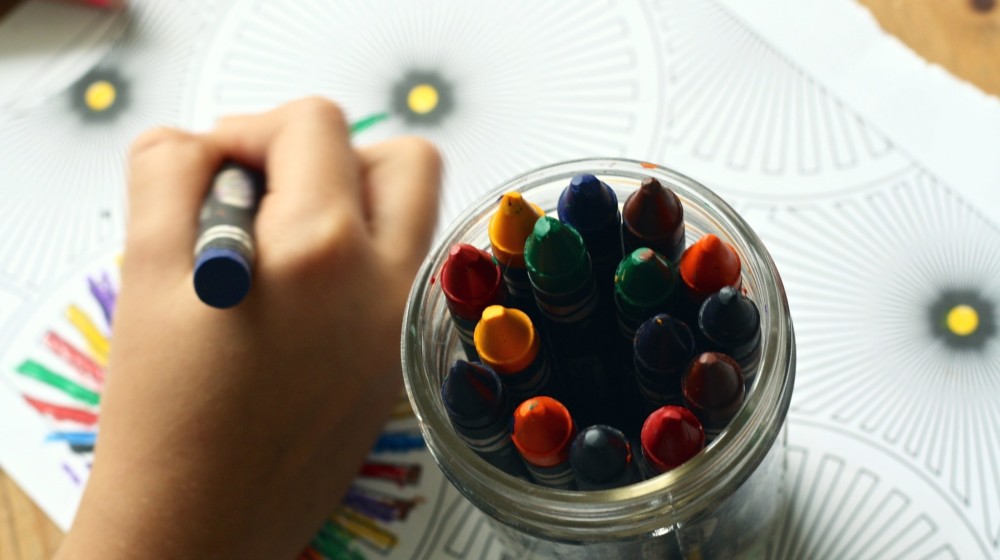 A picture of someone coloring with brightly colored crayons.