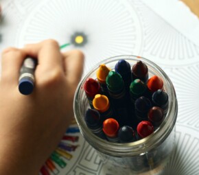 A picture of someone coloring with brightly colored crayons.