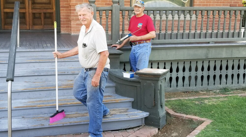 Two Heritage Square volunteers, cleaning and repairing the front steps of Rosson House.