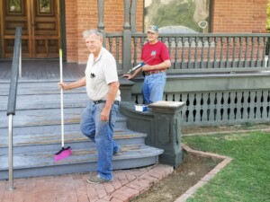 Two Heritage Square volunteers, cleaning and repairing the front steps of Rosson House.
