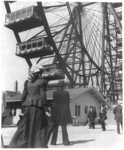 A picture taken in the late 1890s of people looking up at a large Ferris Wheel.