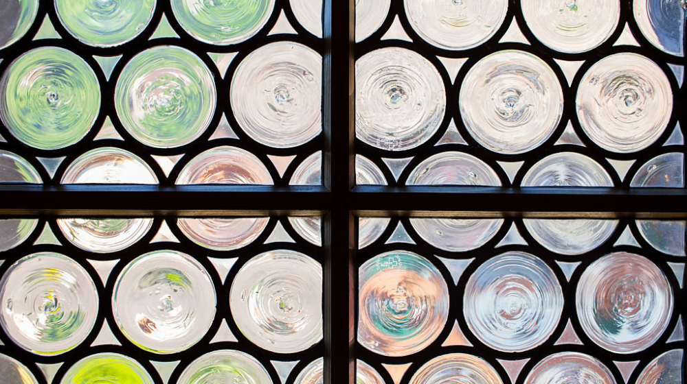 An antique window with small, circular pieces of glass set together within a window frame.