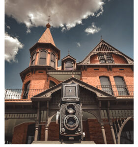 A picture looking up at Rosson House, with an antique camera in the foreground.