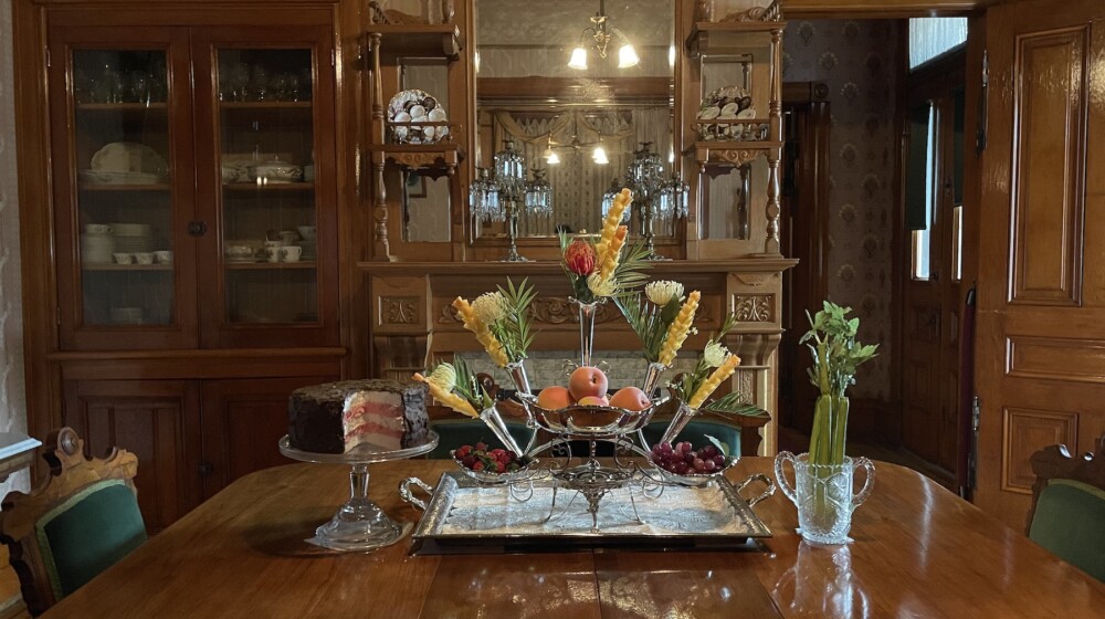 The Rosson House dining room with a tray, cake stand, multi-tiered centerpiece, berry bowls, and a celery vase, all on display.