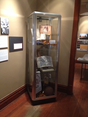 An exhibit case from the Phoenix Indian School Legacy Project exhibit, with pictures, a yearbook, awards, and musical instruments.