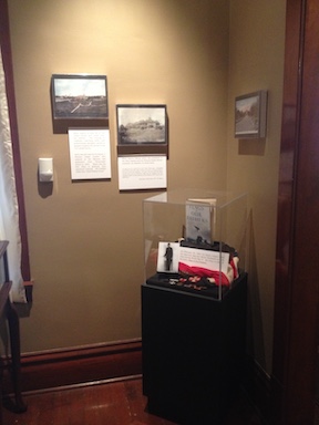 An exhibit wall and case from the Phoenix Indian School Legacy Project, featuring pictures of the Phoenix Indian School, and information about Phoenix Indian School students who served in the US armed forces.