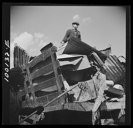A boy standing atop a pile of scrap metal during a metal recycling drive in Washington, DC, May 1942.