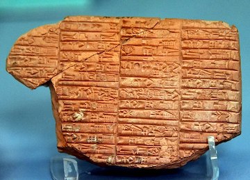 A picture of a broken clay tablet with cuneiform writing.
