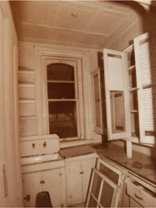 A picture of the pantry at Rosson House before it was restored. All of the walls, shelves, and cabinetry have been painted white, and the kitchen sink has yet to be moved to its original position in the kitchen.
