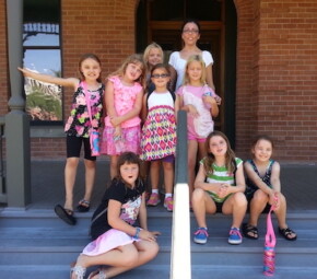 A picture of a group of young students and their chaperone on the steps of Rosson House.