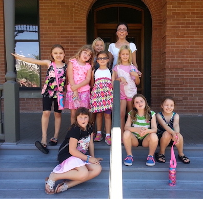 A picture of a group of young students and their chaperone on the steps of Rosson House.