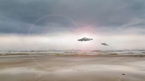A photoshopped picture of two unidentified flying objects hovering over ocean waves on a beach.