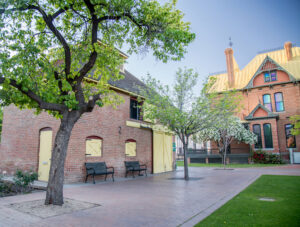 A picture of the Burgess Carriage House and Rosson House at historic Heritage Square, with green grass and trees with bright, new leaves.