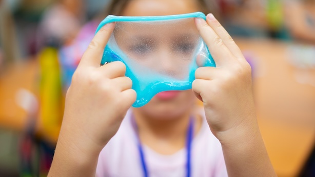 A picture of a child holding up and looking through blue slime.