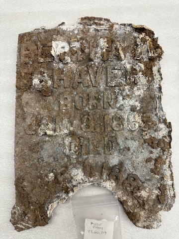 A picture of a very corroded metal grave marker.