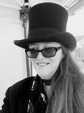 Black and white photograph of author Tam Chronin wearing sunglasses and a top hat.