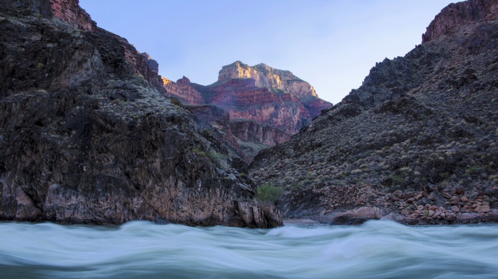 A picture of the Colorado River with tall mesas in the background.